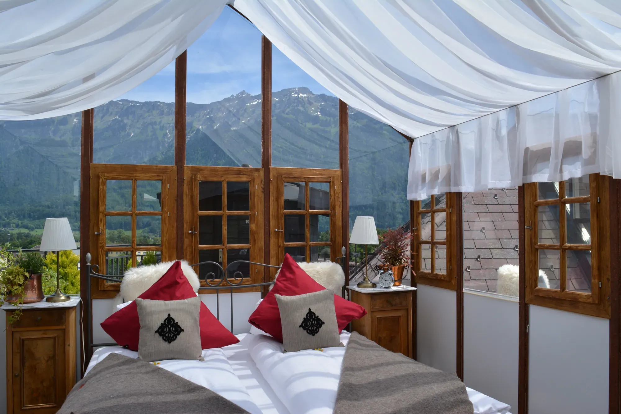 Himmelbett im Glaspavillon auf der Dachterrasse, durch die Fenster die Berge